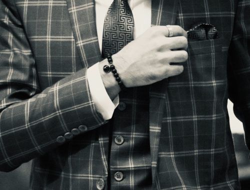 homme en costard qui porte un bracelet en perle